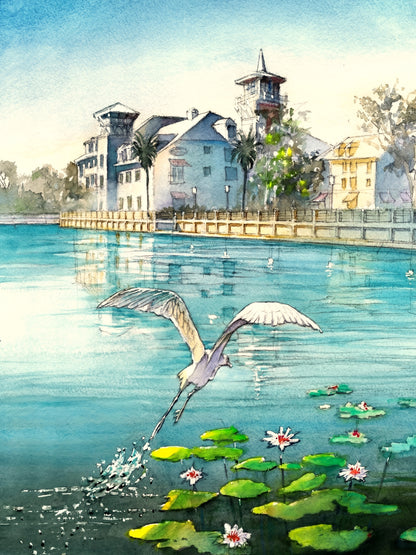 Watercolor painting of Celebration Florida lake with a heron flying above lily pads and calm blue water